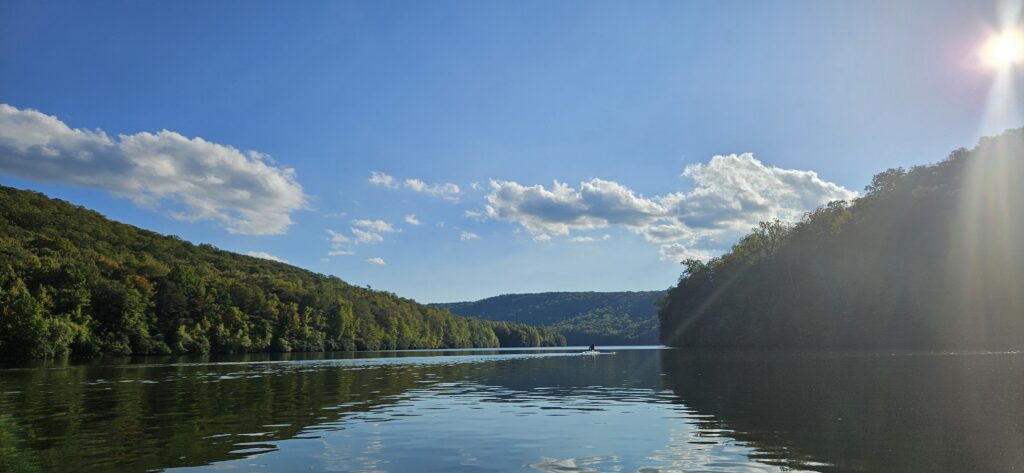 An image of a peaceful reservoir surrounded by tree-filled hills