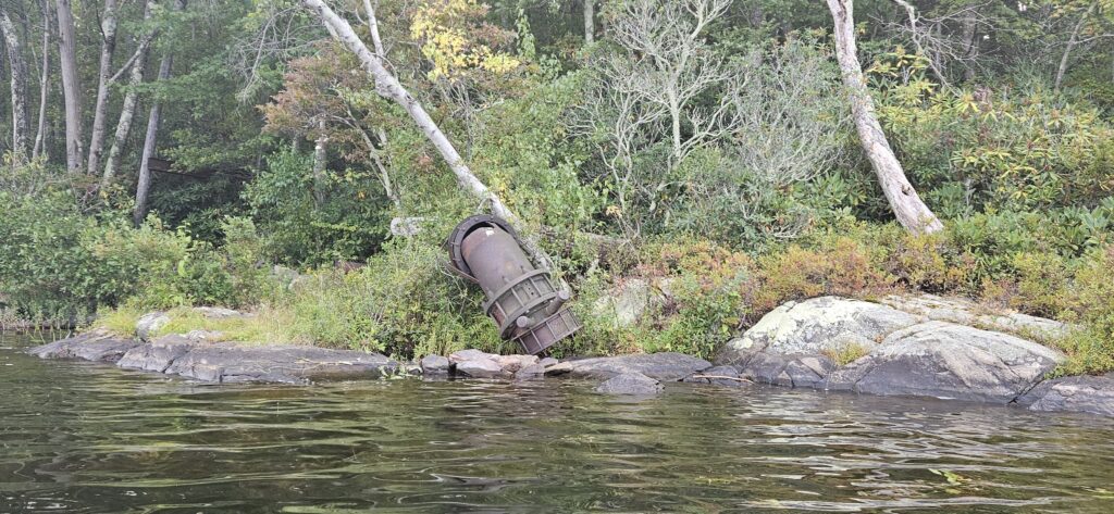 An image of a rusty pipe extending into a lake