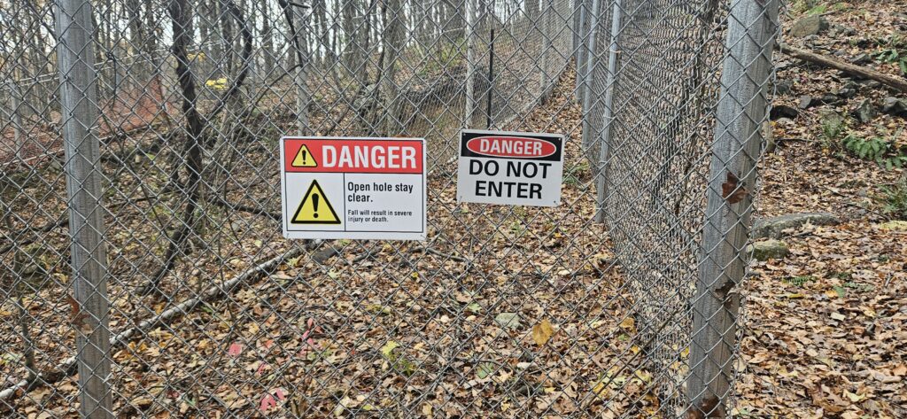 An image of two signs describing danger from an open mine hole